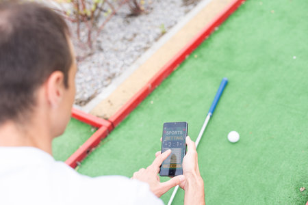 Touch screen in hand, tablet on golf club. smartphone with a sports betting applicationの写真素材