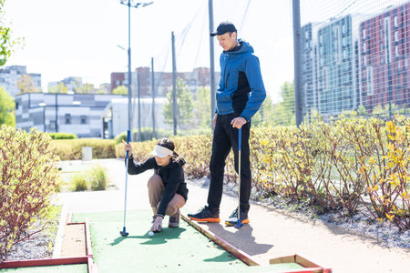 young handsome father teaching his little daughter how to play golfの写真素材