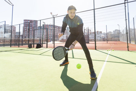 Man playing padel in a green grass padel court indoor behind the netの写真素材