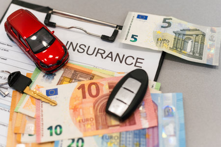 Top view of car insurance claim form with car key and car toy on deskの写真素材