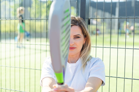 Happy female paddle tennis player during practice on outdoor court looking at camera. Copy space.の写真素材