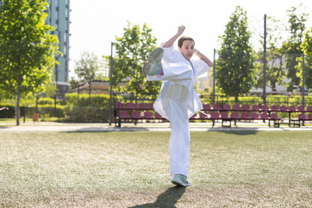 Young active girl wearing in white kimono with white belt performing martial arts kick skills. sporty karate woman improving fight technique on Chinese bridge. concept of sport.の写真素材