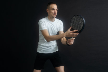 Beautiful man playing paddle tennis, racket in hand concentrated look. Young sporty boy ready for the match. Focused padel athlete ready to receive the ball. Sport, health, youth and leisure conceptの写真素材