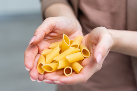 Mostaccioli pasta in the palm of a hand isolated over a white background.の写真素材