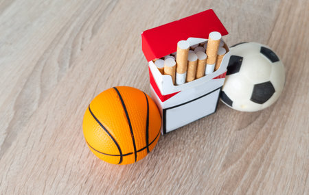 Smoking or sports. Sport ball and pack of cigarettes on table background. Top viewの写真素材
