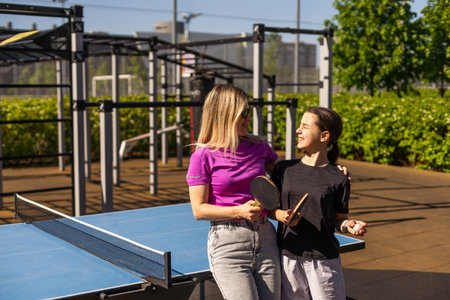 Adult woman instructor teaching girl play table tennisの写真素材