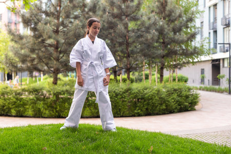 Young active girl wearing in white kimono with white belt performing martial arts kick skills. sporty karate woman improving fight technique on Chinese bridge. concept of sport.の写真素材