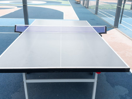 tennis table on the park area around lawn blue white metallic. sun game players, nobody, school yard