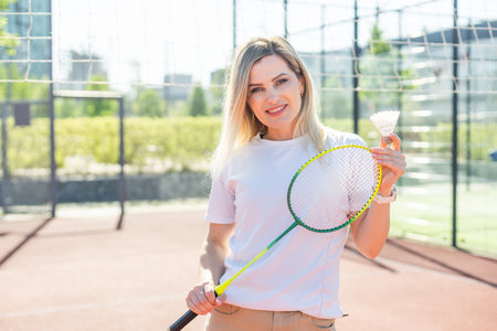 Beauty sport. Pretty young woman in fitness clothes. Slim body. Look at camera. Badminton exercise. Power wellness. Workout lifestyle. Training position.の写真素材