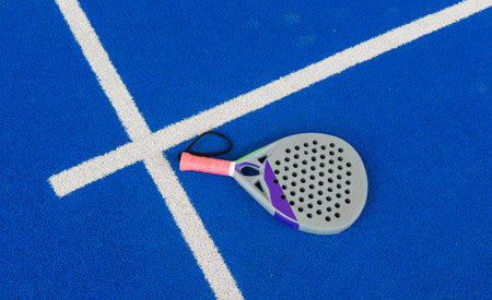 Paddle tennis: Paddel racket and ball in front of an outdoor courtの写真素材
