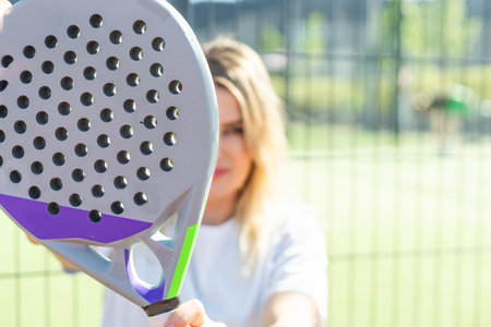 Happy female paddle tennis player during practice on outdoor court looking at camera. Copy space.の写真素材
