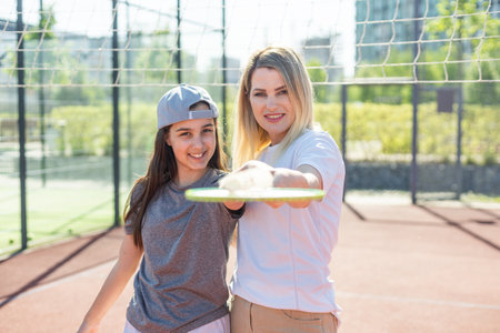 Mother and daughter are playing badminton outside in the yard on summer hot dayの写真素材