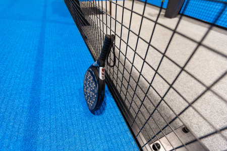 Black professional paddle tennis racket and ball with natural lighting on blue background. Horizontal sport theme poster, greeting cards, headers, website and appの写真素材