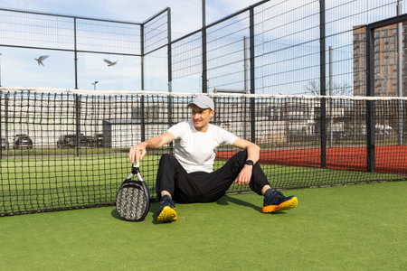 Young man playing paddle tennis on a green court, wearing a t-shirt.Sports concept.Copy spaceの写真素材