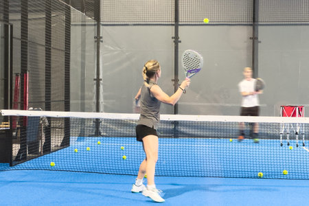 Monitor teaching padel class to woman, his student - Trainer teaches young girl how to play padel on...