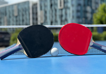Two table tennis rackets and balls on a blue table with net.の写真素材