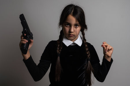 A girl with braids in a gothic style on a dark background with weaponsの写真素材