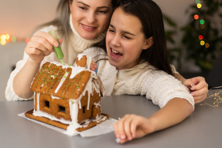 Family decorating gingerbread house on Christmas eveの写真素材