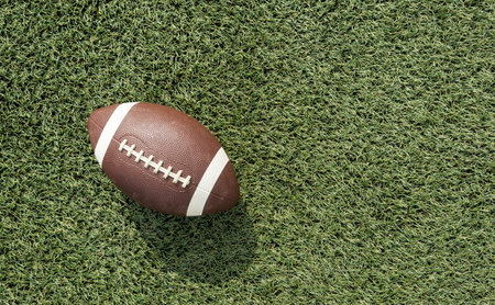 A brown leather American football on a green football field