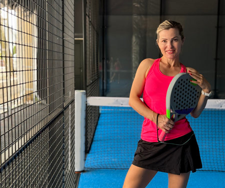 Portrait of beautiful woman playing padel tennis court indoorの写真素材