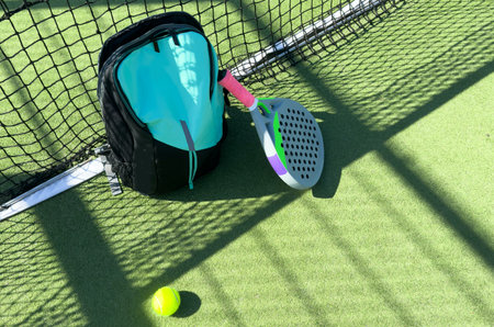 Blue bag with tennis padel racket and ball on grassy field at tennis court, copy space. Unaltered, sport, competition, green, nature and summer concept.の写真素材