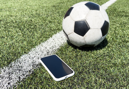 Man use mobile phone, blur image of football field as background.の写真素材