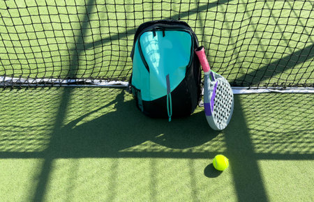 Blue bag with tennis padel racket and ball on grassy field at tennis court, copy space. Unaltered, sport, competition, green, nature and summer concept.の写真素材