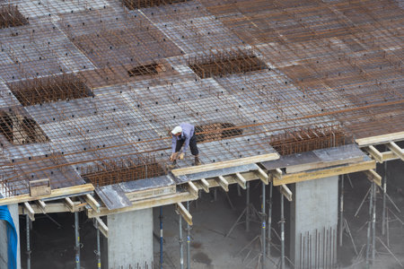 Aerial view of busy industrial under construction site workers working with cranes and excavators. Top view of precast concrete slap floor full of steel. Development high rise architecture building.の写真素材
