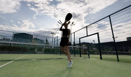 Padel tennis player with racket. Girl athlete with paddle racket on court outdoors.の写真素材