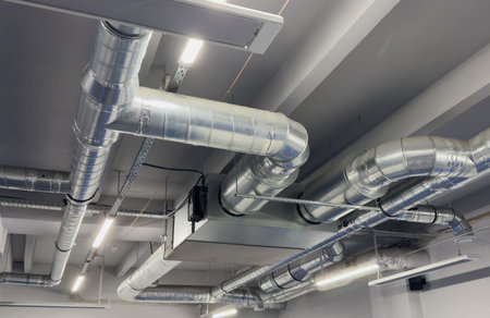 Metal pipes in thermal insulation winding on the ceiling of an industrial enterprise.