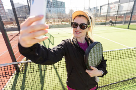 Active young woman trying to beat the ball by Padel racket while playing tennis in the courtの写真素材