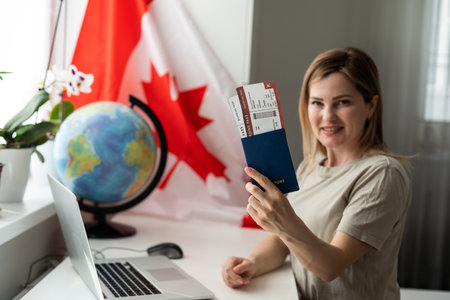 female student sitting with canadian flag and using laptopの写真素材