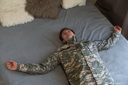 Young man wearing camouflage army uniform relaxing and stretching, arms and hands behind head and neck smiling happy.の写真素材