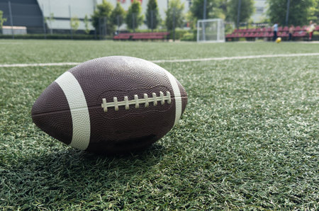 A brown leather American football on a green football fieldの写真素材