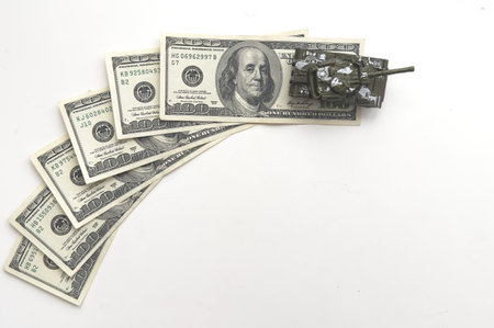 A model of a military tank stands against the background of banknotesの写真素材