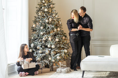 Happy young parents with daughter in the living room celebrate Christmas and New Yearの写真素材