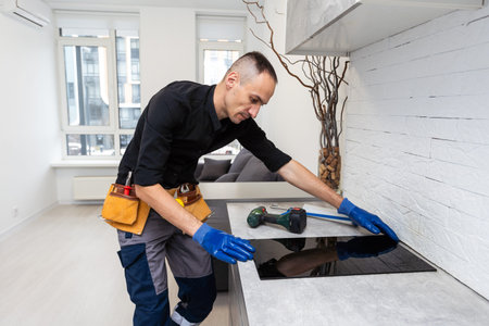 craftsman installs hob in kitchen. Household Appliance Installation Services Conceptの写真素材