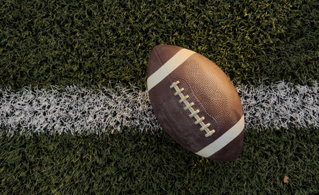 American football ball on green grass field background.の写真素材