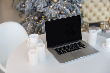 desk with computer against blurred christmas lights backgroundの写真素材