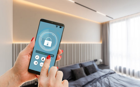 Young woman holding smart phone with launched security application at home. Concept of controlling and managing home security from a mobile deviceの写真素材