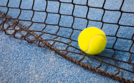 Ball in the shade of the net of a blue paddle tennis court.の写真素材