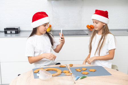 Two girls, sisters, are preparing Christmas cookies in the kitchen and playing around . Christmas, New Year conceptの写真素材