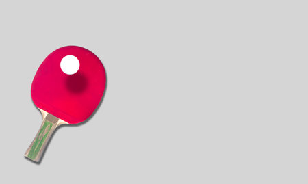 Red ping pong paddle and a white ball on a white background with copy space