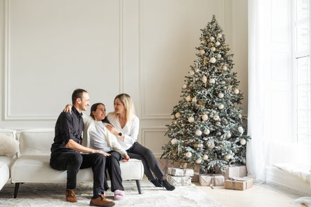 Merry Christmas and Happy Holidays. Mum, dad and child exchanging gifts. Parents and daughter having fun near tree indoors. Loving family with presents in room.の写真素材