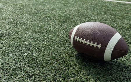 A brown leather American football on a green football field