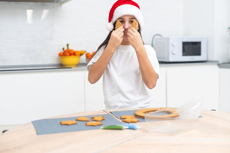 Child girl prepare ginger cookies for Christmas holiday and play with cookie cutters. Christmas...
