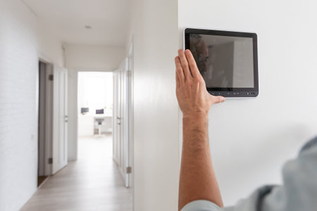Young electrician installing security alarm on wall