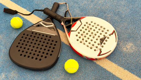 Paddle tennis: Paddel racket and ball in front of an outdoor courtの写真素材