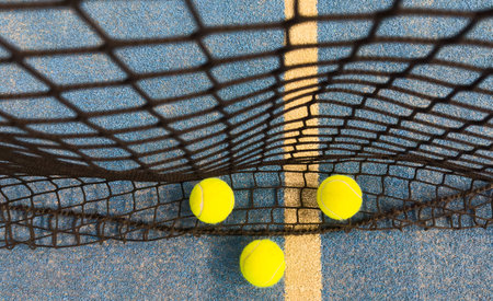 Ball in the shade of the net of a blue paddle tennis court.の写真素材