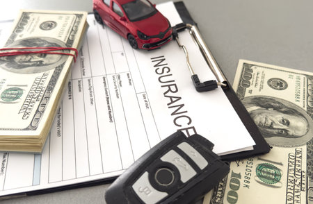Red toy car with money on an insurance contract. Safety concept.の写真素材